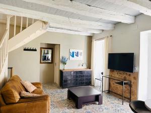 a living room with a couch and a flat screen tv at Les Deux Canards Perdus in Rouffignac Saint-Cernin