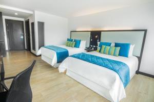 two beds in a hotel room with blue and white at Four Points by Sheraton Cuenca in Cuenca