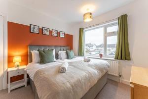 a bedroom with a large bed with an orange wall at Spacious 3-Bed with parking NEAR NEC & BHX AIRPORT in Allesley