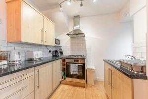 a kitchen with wooden cabinets and a stove top oven at Spacious 3-Bed with parking NEAR NEC & BHX AIRPORT in Allesley