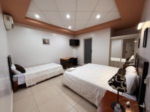 a hotel room with two beds and a television at Rolovi Hotel Xalapa Centro in Xalapa