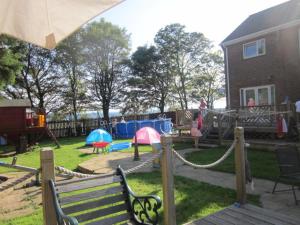 un patio trasero con un parque infantil con columpios en Three Bridges Bed & Breakfast, en Rosyth