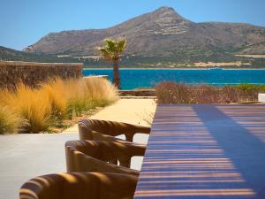 a wooden boardwalk with benches and a view of the water at Farous seaside sunset villa II in Antiparos