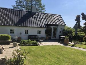 a white house with a black roof and a patio at Heltoften Bed & Breakfast in Nykøbing Mors