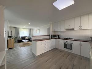 a kitchen with white cabinets and a living room at Southern Comfort in Esperance in Esperance
