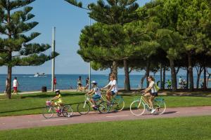 a group of people riding bikes on a path near the beach at apartamento Kottmann in Cambrils