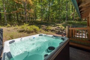 a hot tub on the porch of a cabin in the woods at Tranquil Timber by Railey Vacations in Swanton