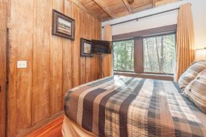 a bedroom with wood paneling and a bed with a tv at Tolson Cabin by Railey Vacations in Oakland
