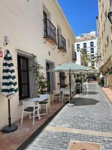 a patio with tables and umbrellas on a street at Zazz Estepona in Estepona
