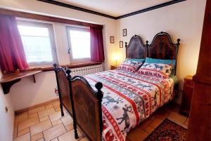 a bedroom with a bed with a wooden headboard and two windows at Dolce Vista in Passo del Tonale