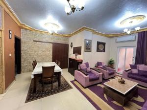 a living room with a table and purple furniture at Jad Apartment in irbid in Irbid