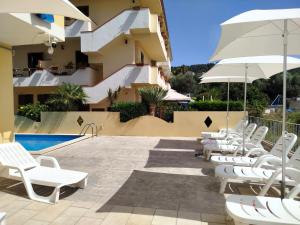 a row of white chairs and umbrellas next to a building at La Playa Del Sol Tropea in Santa Domenica