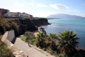 a person standing on a path next to the ocean at L'arco Sul Mare in Balestrate