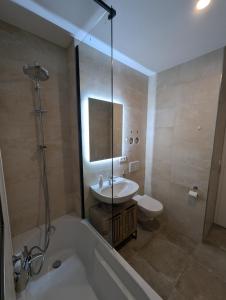 a bathroom with a tub and a sink and a toilet at Wohnen am Wald mit Pool & Sauna in Unterkirnach +5 photos