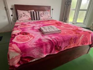 a bed with a pink comforter with a book on it at Sisila villa ella in Ella