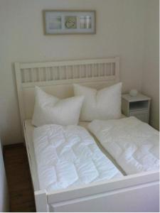 a white bed with white sheets and pillows at Ferienwohnung Michel in Ahlbeck