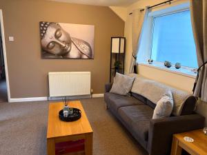 a living room with a couch and a window at Roseus and Mimosa Cottages in Combe Martin