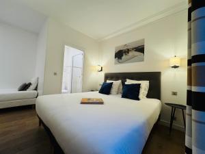a bedroom with a large white bed with blue pillows at Hôtel L'Amiral in Paris