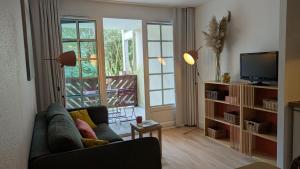 a living room with a couch and a tv at Cosy MO-MAÂ Golf, Océan et Plages in Moliets-et-Maa