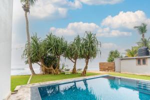 a villa with a swimming pool and palm trees at Surfside Serenity - SS Beach in Ahangama