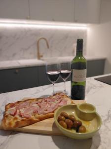 a bottle of wine and a slice of pizza and wine glasses at Casa Maria in Żabbar