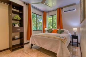 a bedroom with a bed with orange curtains and a window at AroCocles Apartments in Cocles