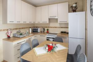 a kitchen with white cabinets and a table with flowers on it at noclegi u zabki in Ełk