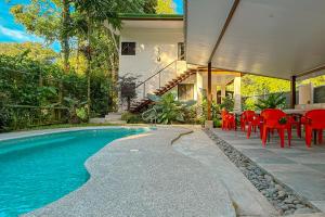 a house with a swimming pool with red tables and chairs at AroCocles Apartments in Cocles