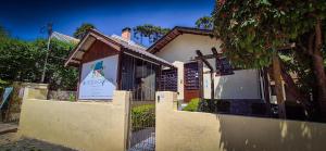 a house with a fence and a sign in the window at A Nossa Casinha Capivari - 400m do Parque Capivari in Campos do Jordão +57 photos