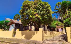 a fence in front of a house with a tree at A Nossa Casinha Capivari - 400m do Parque Capivari in Campos do Jordão