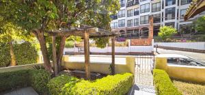 a tree with a wooden structure next to a building at A Nossa Casinha Capivari - 400m do Parque Capivari in Campos do Jordão