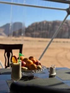 a plate of fruit on a table with a view of the desert at RUM HORIZON BUBBlE LUXURY CAMP in Wadi Rum
