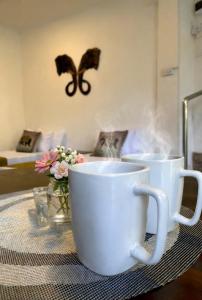 two coffee cups on a table with a butterfly on the wall at Ark Cabin Villa in Kandy