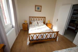 a bedroom with a bed and two night stands and two windows at Gîte Aux Tuileries in Noaillan
