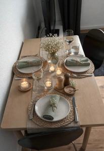 a wooden table with plates and candles on it at Klytti‘s Pension in Sendenhorst