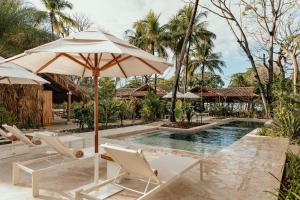 ein Schwimmbecken mit Stühlen und einem Sonnenschirm und ein Pool in der Unterkunft Hotel Fermata in Playa Santa Teresa