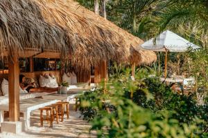 ein Ferienresort mit Tischen und Stühlen und einer Strohhütte in der Unterkunft Hotel Fermata in Playa Santa Teresa