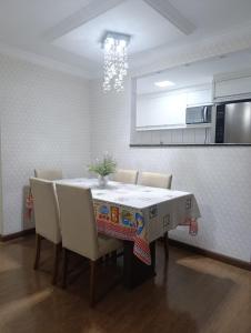 a dining room table with chairs and a kitchen at Jonas e Selma Apartmento 3 quartos in Araucária