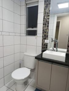 a white bathroom with a toilet and a sink at Jonas e Selma Apartmento 3 quartos in Araucária