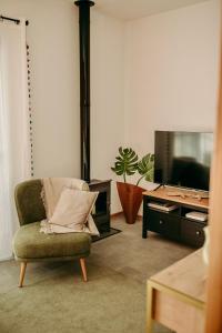 a living room with a chair and a tv at Coração da Quinta in Algarvia