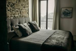 a bedroom with a bed with pillows and a window at Coração da Quinta in Algarvia