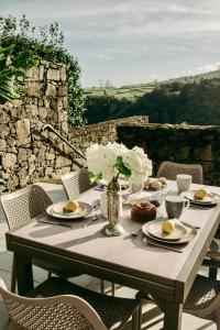 a table with plates of food and flowers on it at Coração da Quinta in Algarvia
