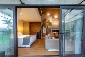 a bedroom and living room with a bed and sliding glass doors at Ananaí Chalés Exclusivo para Casais in Pomerode