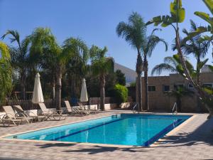 a swimming pool with chairs and umbrellas and palm trees at Harmonia Home in Paralimni