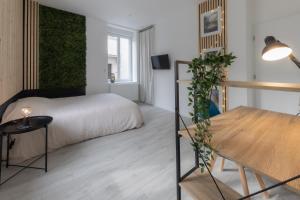 a bedroom with a bed and a table with a plant at L'Évolution, 1 suite et jardin privé in Vesoul
