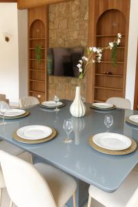 a blue table with white plates and a vase with flowers at Refúgio em Atibaia in Atibaia