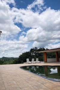 a swimming pool with two chairs and a pavilion at Refúgio em Atibaia in Atibaia