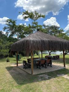 a picnic shelter with benches and a grass roof at Refúgio em Atibaia in Atibaia