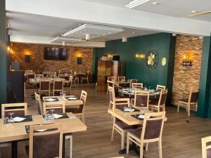 a restaurant with wooden tables and chairs and a brick wall at Logis Hôtel du Commerce in Volvic