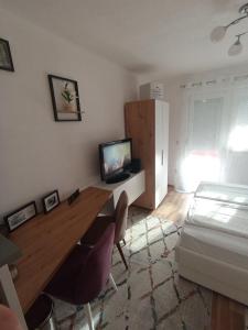 a bedroom with a desk with a television and a bed at SWEET APT Zenica in Zenica